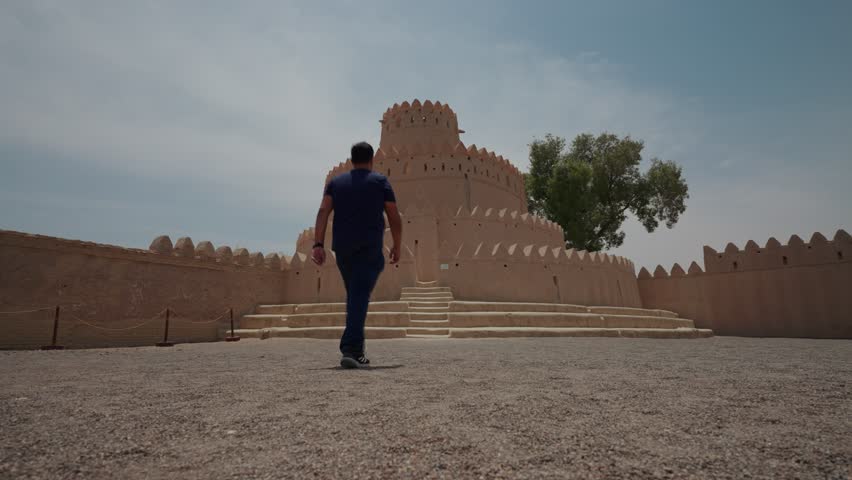 A back shot of adult man wandering in the Al Jahili Fort on a sunny day in Al Ain city, Abu Dhabi, United Arab Emirates