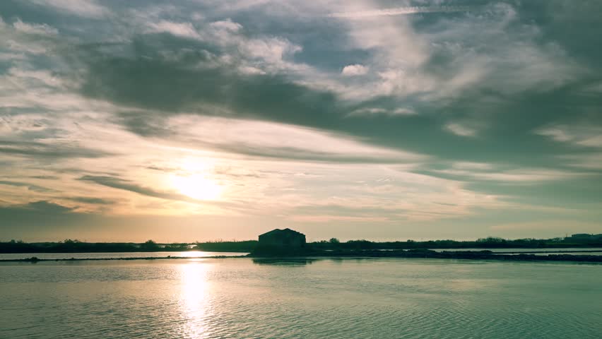 A serene afternoon scene unfolds in Qigu, Tainan City, Taiwan, showcasing the unique landscape of salt fields with a dramatic purple-hued sky and a silhouetted tree.
