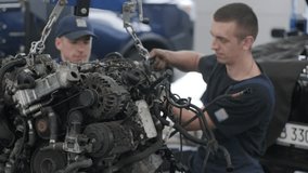 Workers adjusting automotive engine components on hoist. - Powered by Shutterstock - Get 15% off with code: PIKWIZARD15