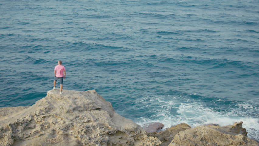Man standing on a rock and enjoying the seascape, holiday by the sea