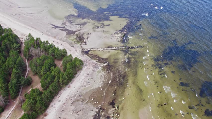 Wooden observation tower in the middle of a lake with a forest in the background. Drone footage. Latvia