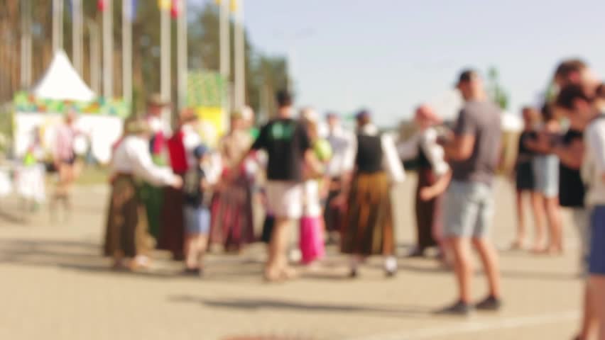 Folk enthusiasts enact ring dance during daytime fair. 