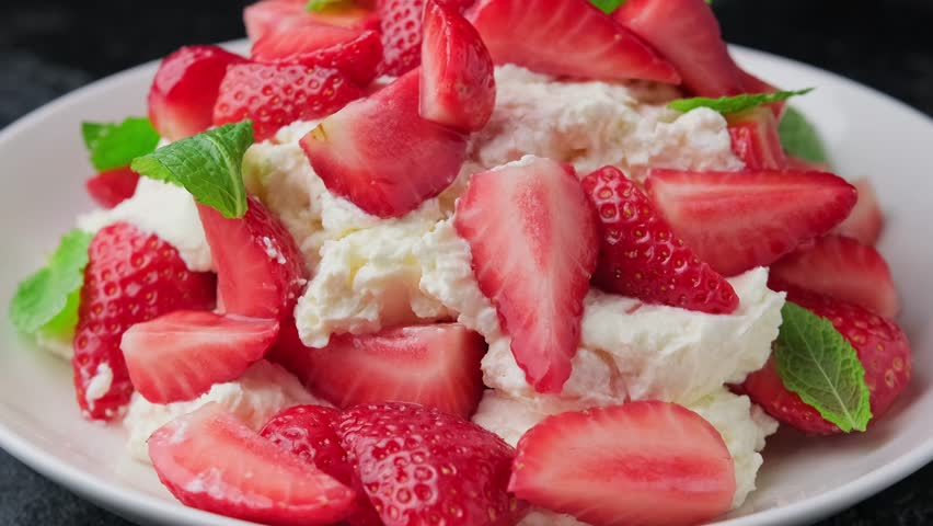 Eating Traditional english dessert eton mess with meringue, whipped cream and fresh strawberries