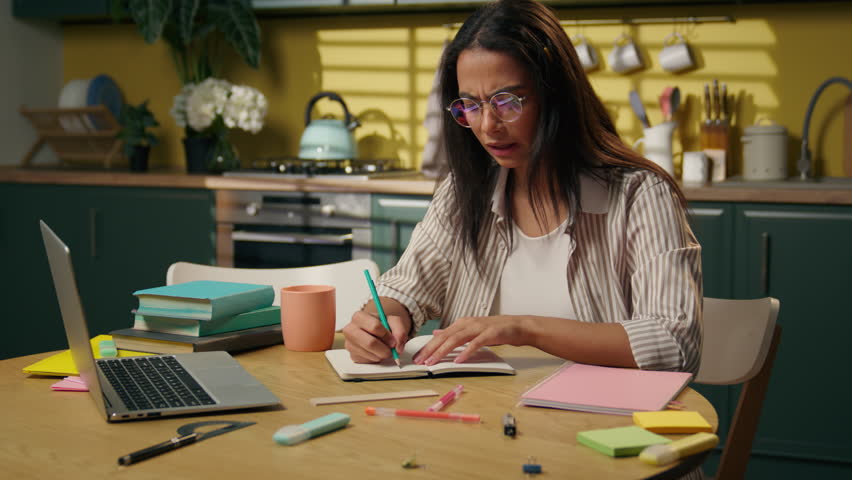 Multitasking girl high school student Latina stressed woman businesswoman distant studying write homework in kitchen female freelancer frustrated problem writing notebook difficult education at home - Powered by Shutterstock - Get 15% off with code: PIKWIZARD15