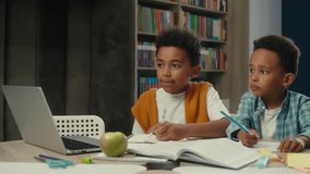 African American little boys siblings brothers children kids students schoolboys pupils studying writing together at desk primary school online education laptop internet teacher video call e-learning - Powered by Shutterstock - Get 15% off with code: PIKWIZARD15