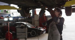 Female mechanic activating angle grinder under auto garage lift, sparking rust removal. Industrial, repair, maintenance, safety, tools, workshop, strength - Powered by Shutterstock - Get 15% off with code: PIKWIZARD15