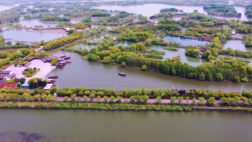 Aerial view of Suzhou Taihu Wetland Park showing waterways, traditional boats, and lush green vegetation