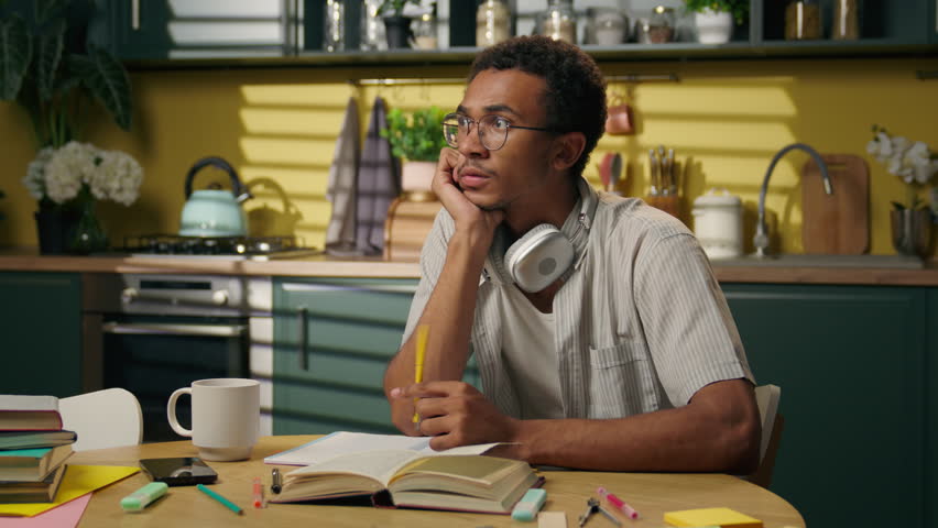 Sad upset thoughtful guy pensive African American man businessman gen z high school student distant study think difficult problem doubt frustrated male homework brainstorm uncertain at home kitchen