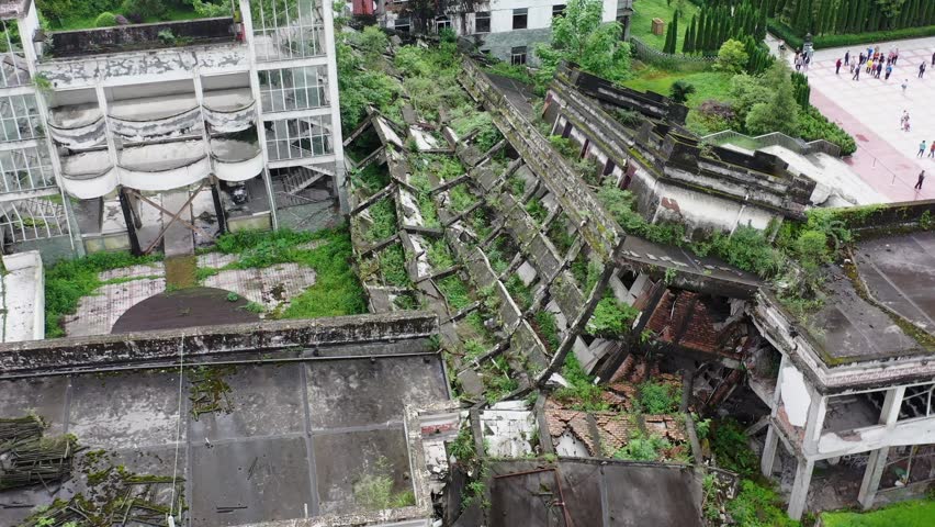 Aerial view of the Wenchuan Earthquake site in Sichuan, China, showing collapsed buildings and overgrown vegetation at memorial park