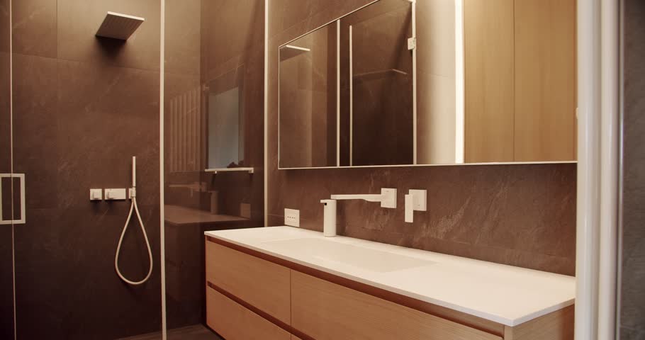 Modern bathroom with simplicity design. Luxury Bathroom Interior, Minimalist interior in brown colors with bathroom accessories , mirror and shower head, bathtub modern design. Luxury cozy Apartment.