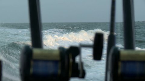 Fishing rods on the back of a boat, on the ocean. pov