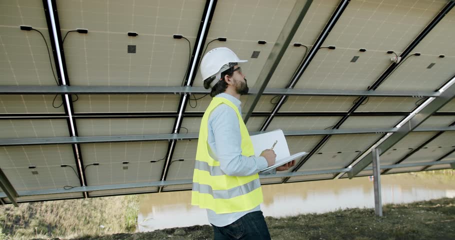 Technician walking in Solar cell Farm. Checking the panels at solar energy installation. Solar cells will be an important renewable energy of the future.
