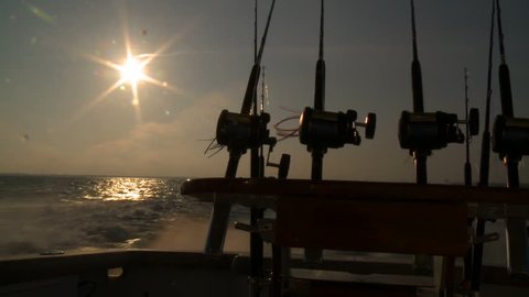 Fishing rods and reels on the back of a boat, on the ocean. silhouette 