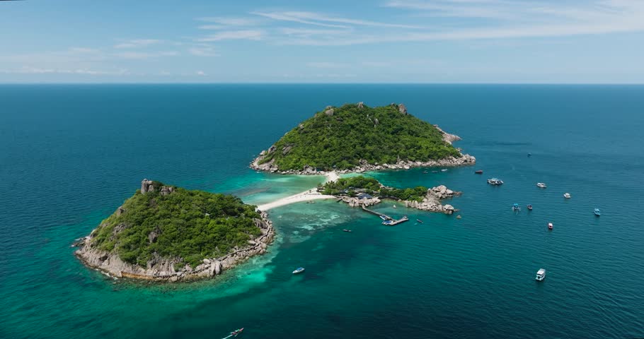Idyllic tropical islands with turquoise waters, vibrant greenery, and a sandy beach surrounded by boats. Nang Yuan, Koh Tao, Thailand.