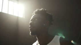 Young pensive African American inmate gazing upward with arms behind head, illuminated by beam of sunlight streaming through barred window in solitary prison cell - Powered by Shutterstock - Get 15% off with code: PIKWIZARD15