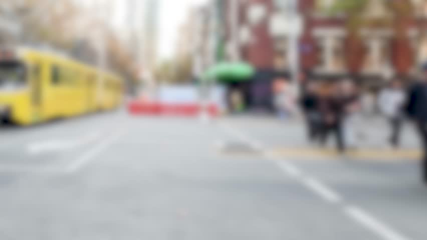 A yellow tram moves through a bustling Melbourne street, capturing urban life with vibrant colors and dynamic motion