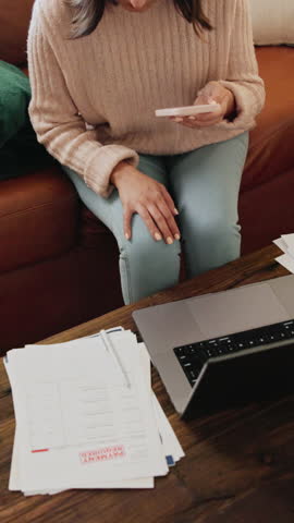 Woman, finance and phone in home for paperwork, debt or above with fintech for easy payment on sofa. Person, smartphone and mobile app with documents, bills and laptop for credit score at apartment
