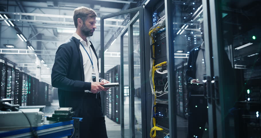 Male IT Technician Working with Server Racks in a Modern Data Center. Providing Maintenance Work and Installing New Hardware for Database and Storage Hard Drives for AI Model Training and Compute