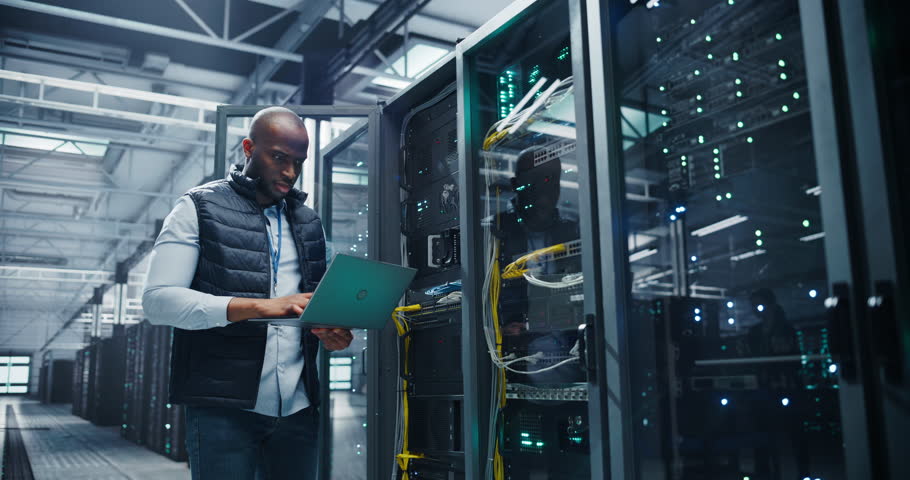 Black IT Technician Working with Server Racks in a Modern Data Center. Providing Maintenance Work and Installing New Hardware for Database and Storage Hard Drives for AI Model Training and Compute