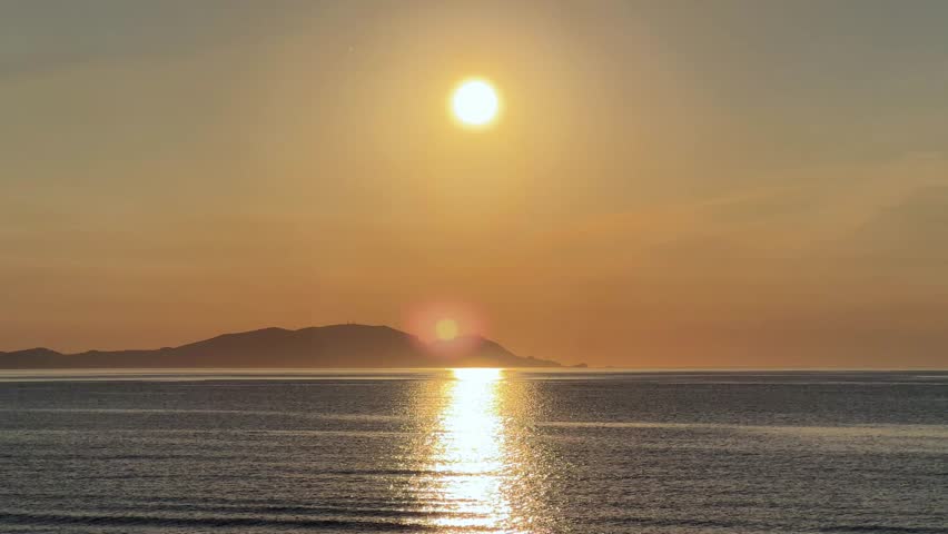 Golden sunset over calm sea at Otaru Dream Beach with distant mountain view