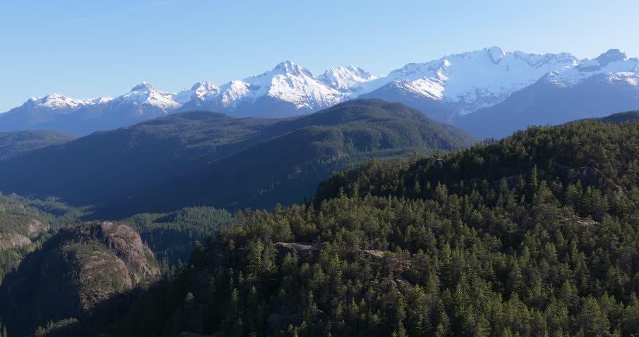Majestic Snow-Capped Mountains Rise Above Vast Green Forests in British Columbia, Canada