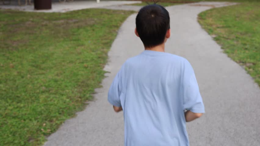 Title: Young man running on the road in park


