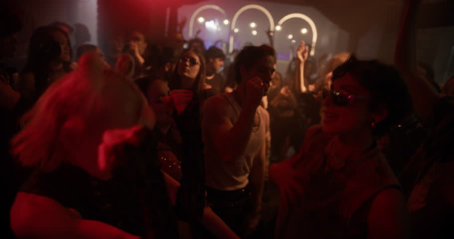 Dynamic Footage of a Crowded Modern Nightclub with Diverse Beautiful People Dancing to Fast-paced Electronic Music. Lights Pulse in Sync with the Beat. Ecstatic, Youthful and Hedonistic Mood