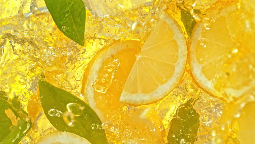 Super Slow Motion Shot of Pouring Lemonade on Fresh Lemon Slices, Ice and Green Leaves at 1000fps.