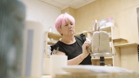 Skilled ceramist molding wet clay on a rotating stand, demonstrating pottery techniques in her workshop - Powered by Shutterstock - Get 15% off with code: PIKWIZARD15