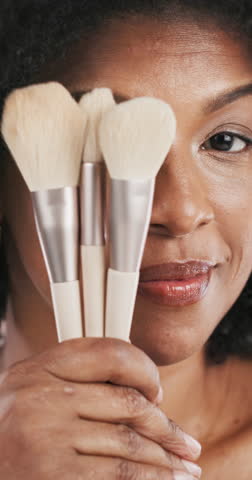 African woman, face and makeup brush for beauty with smile, playful and equipment in closeup. Mature person, happy and cosmetic tools with pride, results and foundation with transformation in Kenya