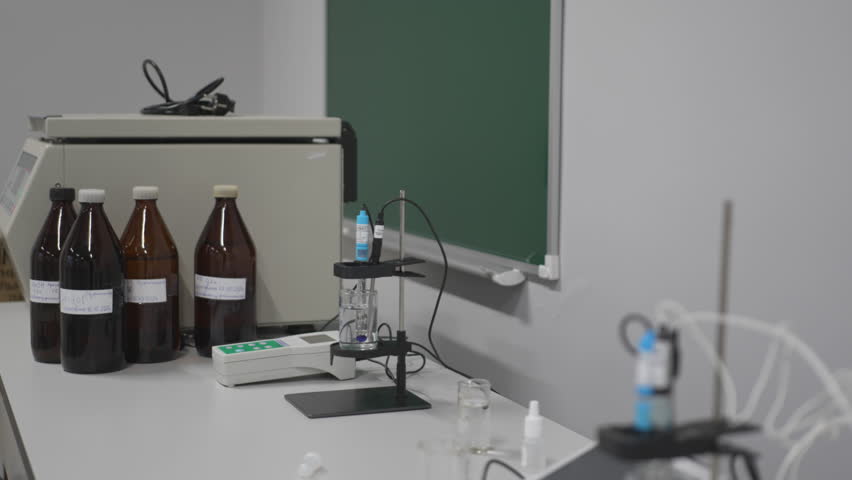 PH meter surrounded by transparent flasks and beakers. Clean arrangement supports precise chemical measurements during learning process