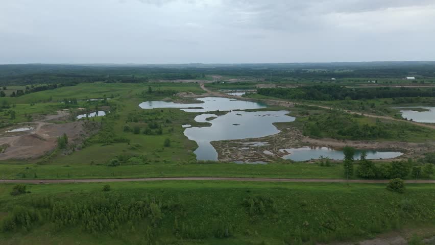 Aerial Flyover Of Lakes And A Road In A Operational Gravel Pit Quarry In Caledon, Ontario, Canada.
