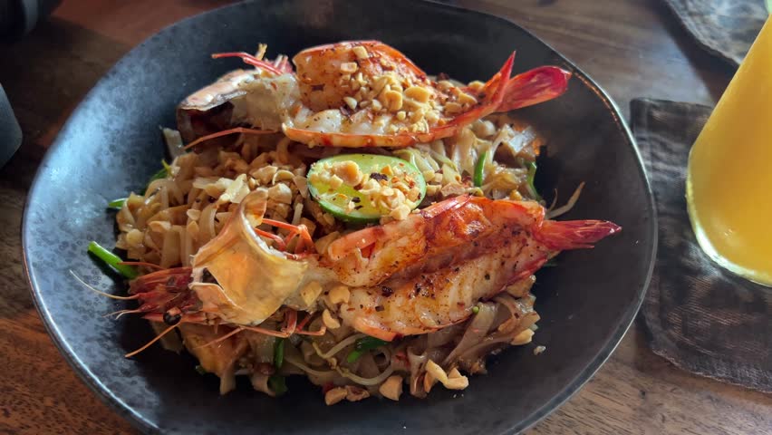 Delicious fried noodles served with chili oil and grilled shrimp