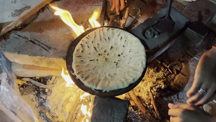 A slow-motion top view of making tortilla on fire outdoors