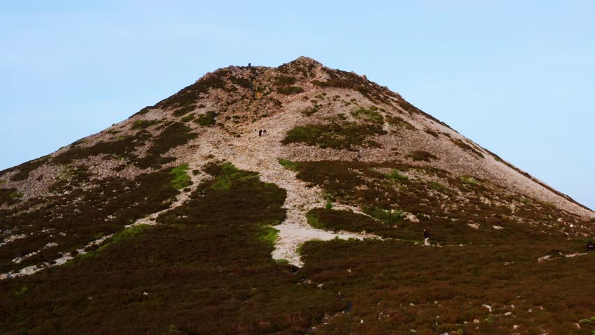 Drone moves slowly toward the Sugar Loaf trail as a hiker begins ascent with others ahead and resting at the top
