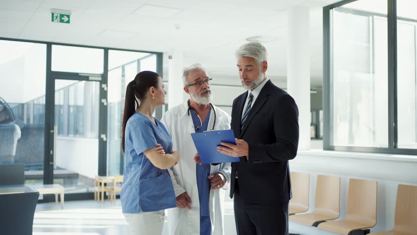 Medical sales representative presenting new medication to doctors, standing hospital hallway. - Powered by Shutterstock - Get 15% off with code: PIKWIZARD15