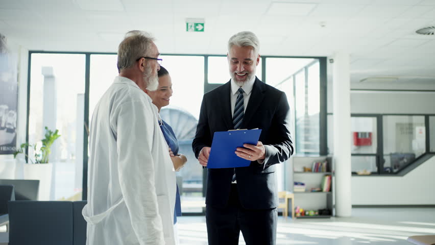Medical sales representative presenting new medication to doctors, standing hospital hallway.