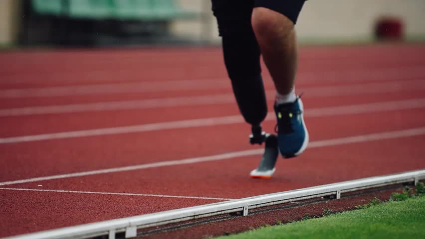 Runner with prosthetic leg trains on athletic track in bright sunlight during afternoon practice session