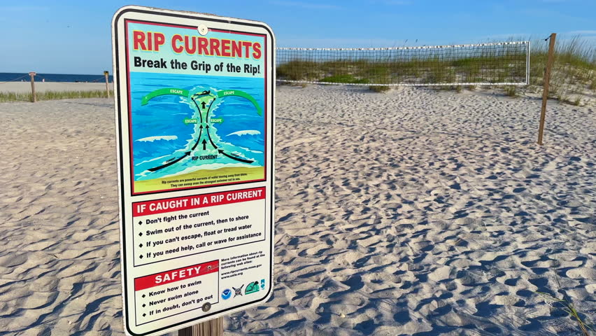 Safety sign warns swimmers of rip currents near coastal beach dunes