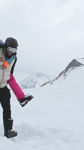 Vertical background of laughing couple enjoy romantic piggyback ride in snowy winter landscape, expressing happiness, love, freedom, carefree vacation, joyful relationship, bonding, playful adventure