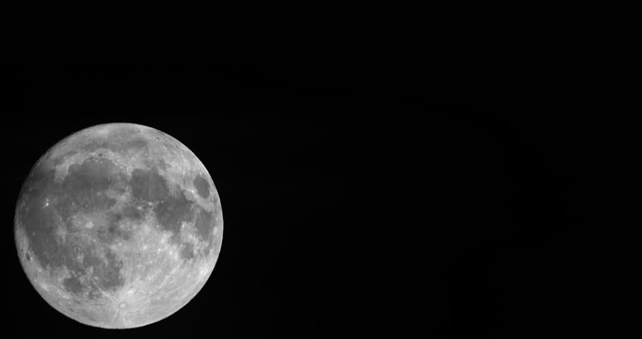 A timelapse of super closeup of full moon rising in a dark sky, and an airplane flew across