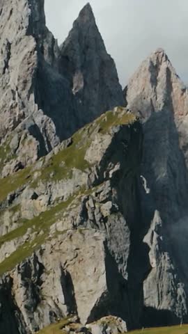 Sharp Rocky Mountain Peaks with Grass Slopes Under Cloudy Sky
