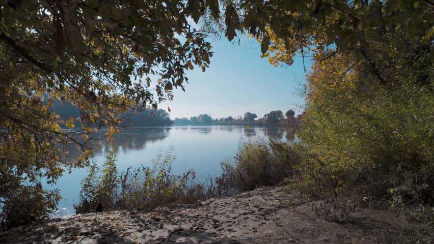 A scenic footage of the tranquil Sacramento River with green vegetation on the shorelines on a sunny day in Sacramento, California, USA