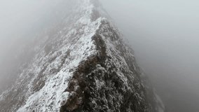 A Drone footage of Snowdonia Rugged Peak with snow covered rocks behind fog - Powered by Shutterstock - Get 15% off with code: PIKWIZARD15