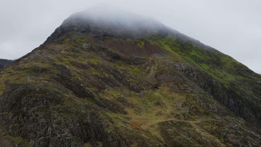 A Drone footage of a track in Snowdonia National Park and fog covering rocky peak