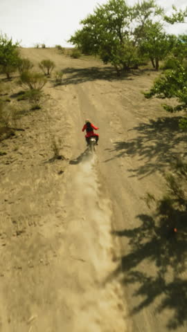 Rider enjoys motorcycle trip in hilly valley fpv drone. Inspired racer rides competing for championship in desert racing. Motocross sports event