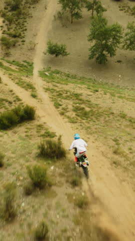 Motorcyclist climbs on dusty hill at racing fpv. Motocross sportsman rides powerful motorbiker at scenic highland. Conquering wilderness on vehicle