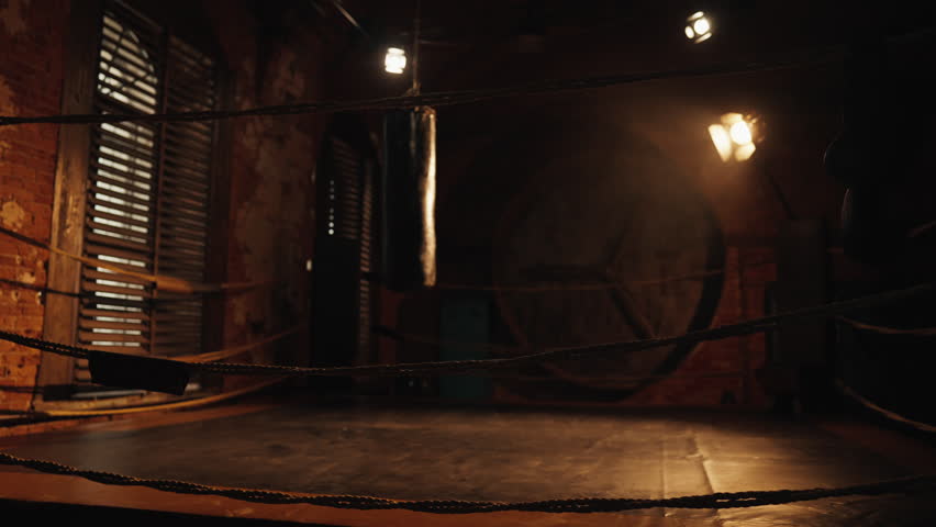 Inside authentic boxing club, ring for training and fighting, nobody in dark gym . Do sport and live active life, empty sports hall in modern fitness center, self-defense class, professional equipment