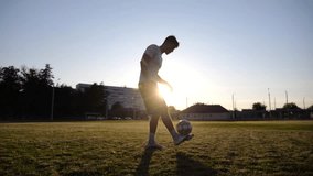 Professional footballer juggling soccer ball on stadium at sunset. Young man kicking ball at green field. Sportsman practicing tricks at meadow with sunlight at background. Freestyle football concept - Powered by Shutterstock - Get 15% off with code: PIKWIZARD15