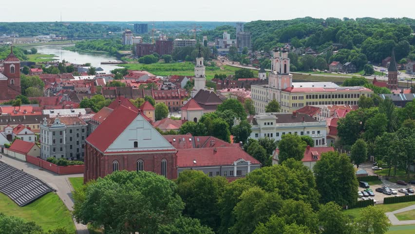 A drone view of Kaunas Old Town with its churches, town hall, river, greenery and red buildings on a sunny beautiful day in Lithuania